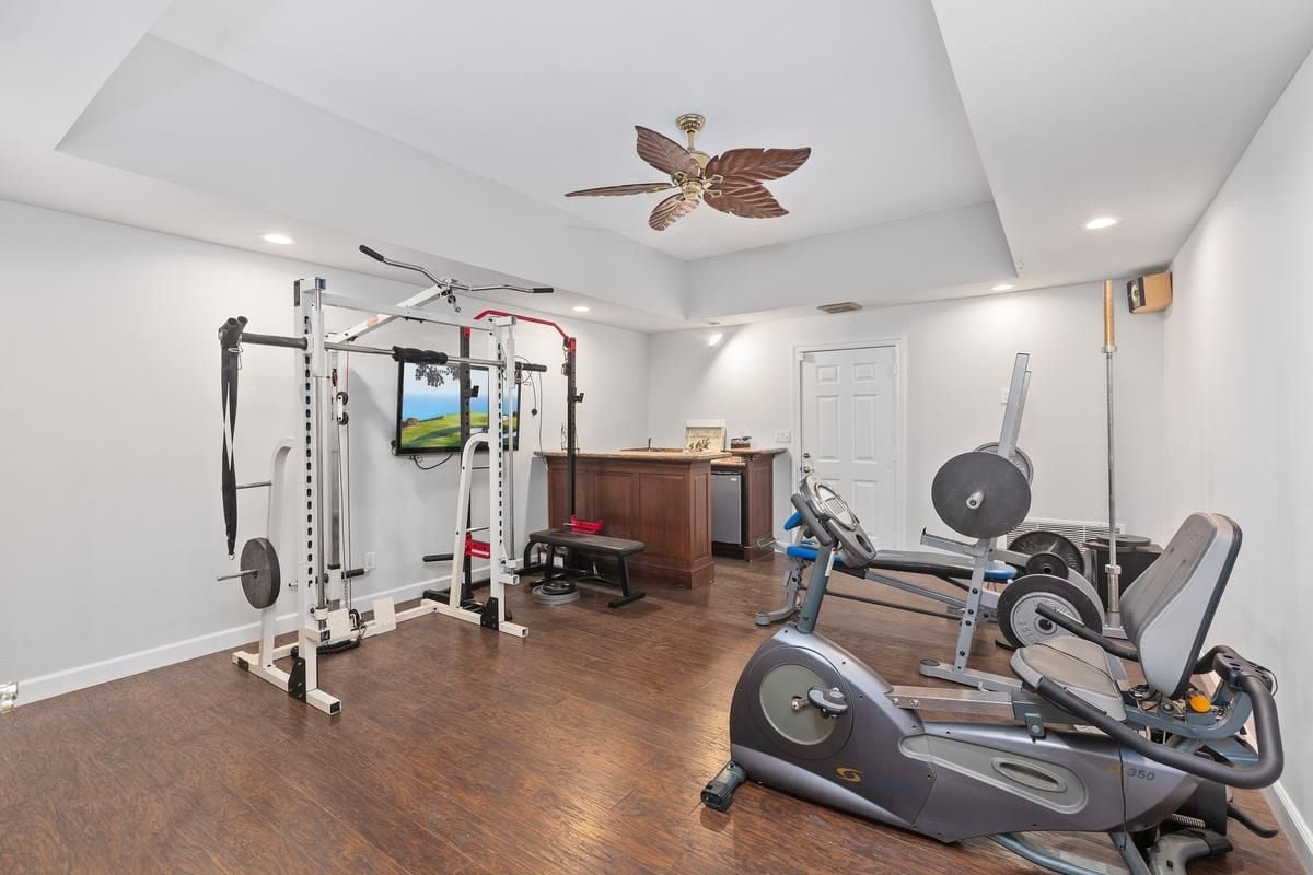 A home gym with a TV, ceiling fan, and gym equipment.