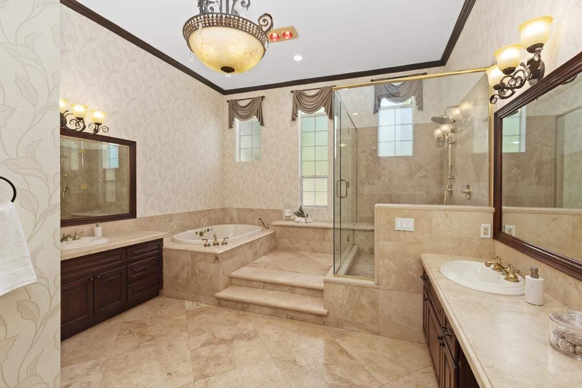 A bathroom with a countertop, vanity, mirror, cabinets, tiled floor, bathtub, and shower room.