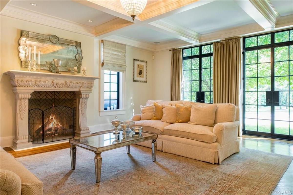 Living room with a fireplace, chandelier and coffered ceiling.