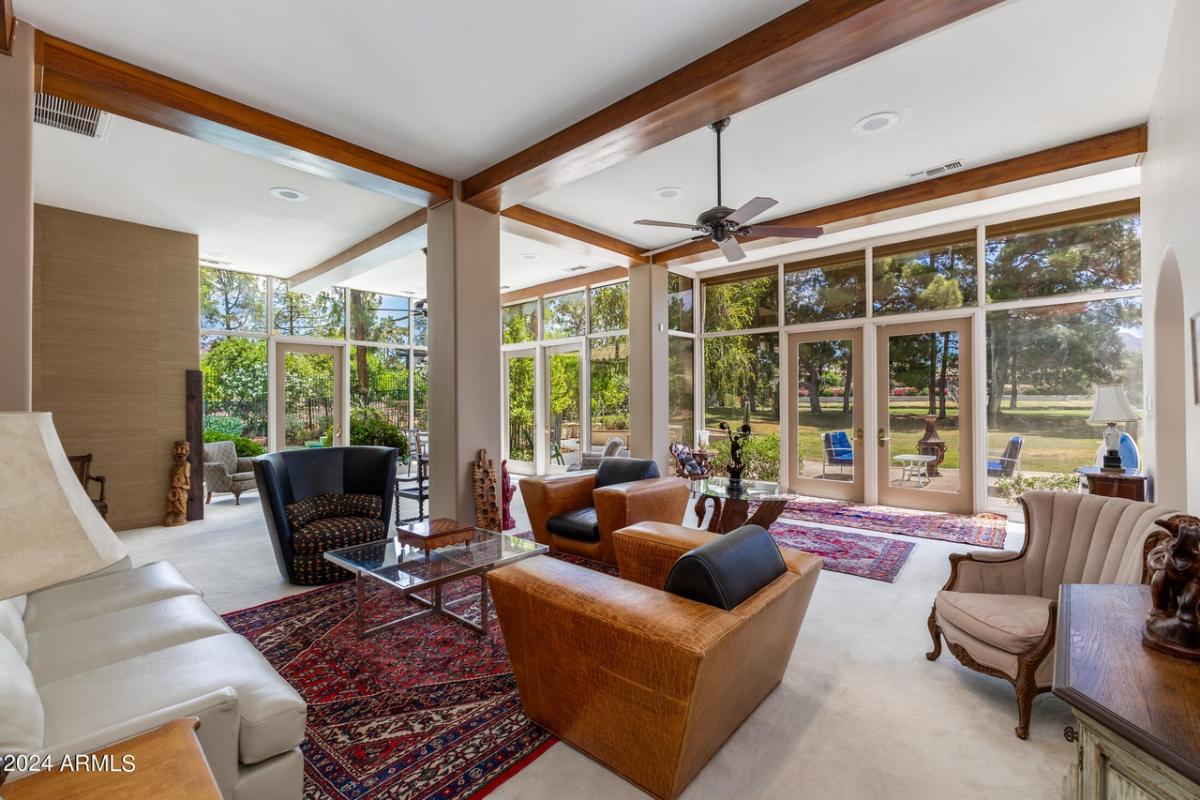 Living room with vaulted ceiling, glass walls and tile flooring.
