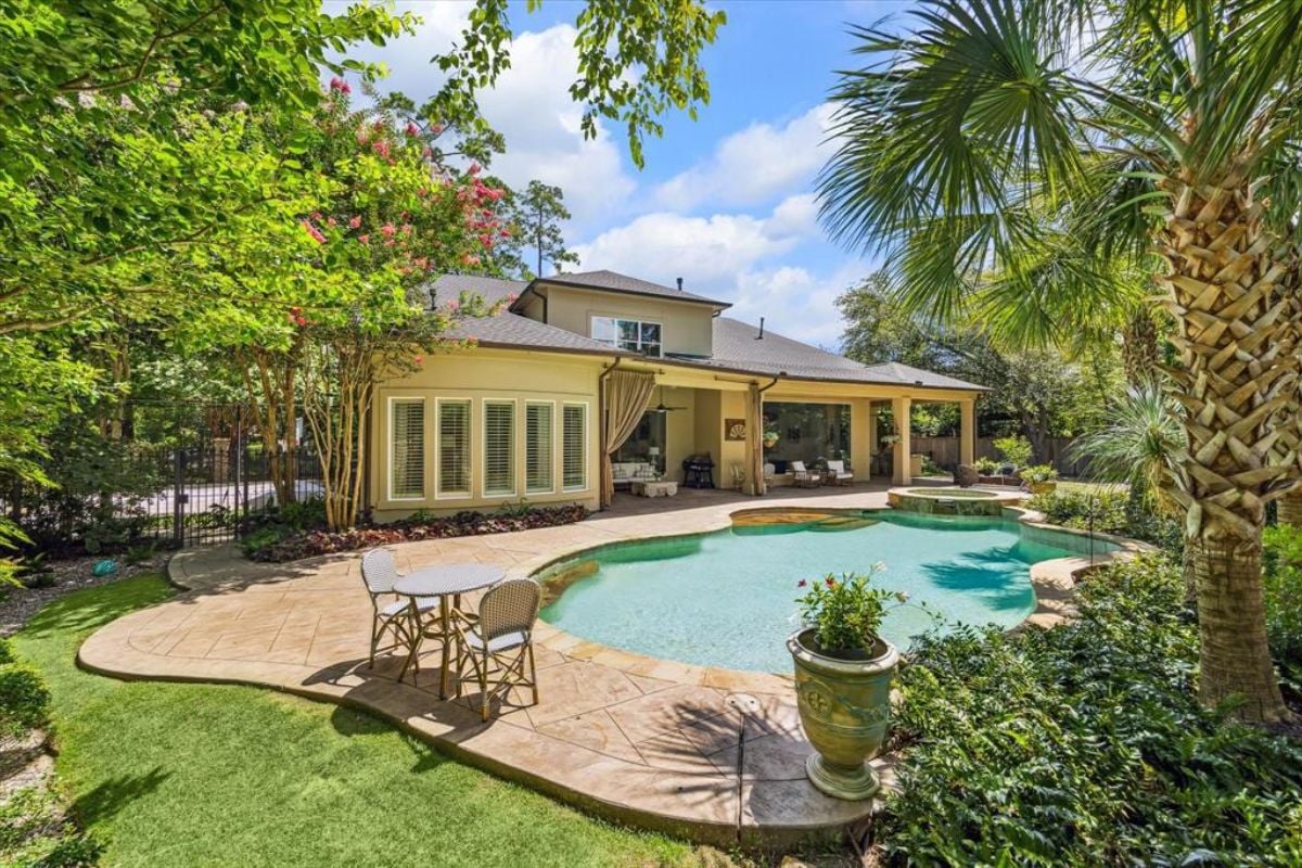 A swimming pool with a jacuzzi surrounded by plants and trees.