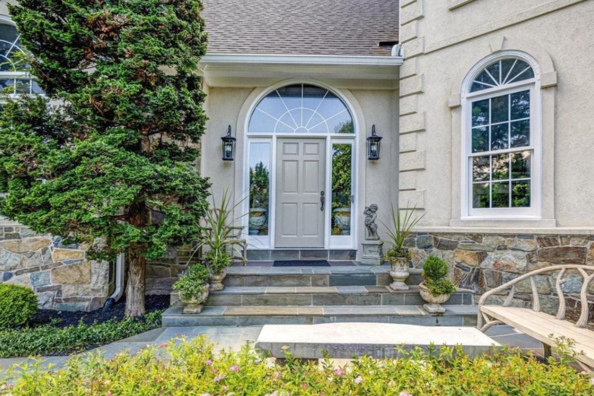 A front entry with plants and a tree.