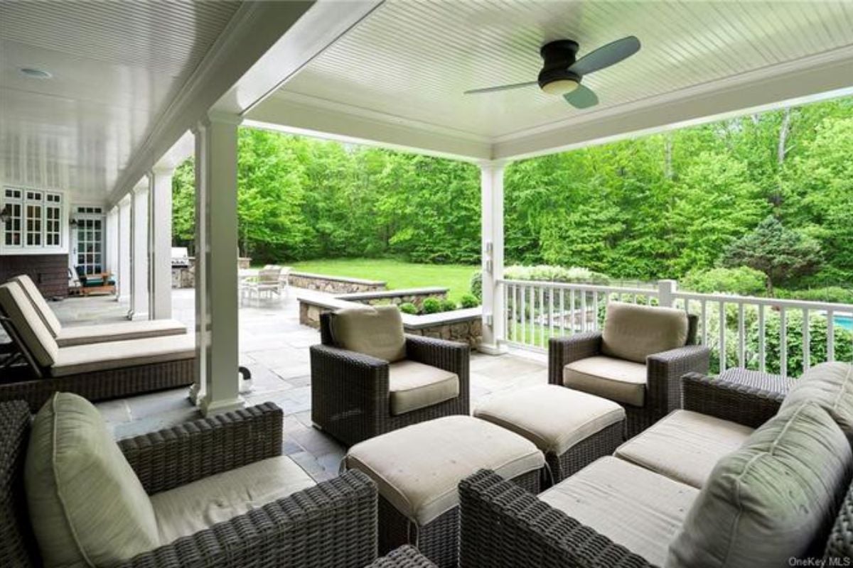 A porch with a ceiling fan, chairs, and a couch.