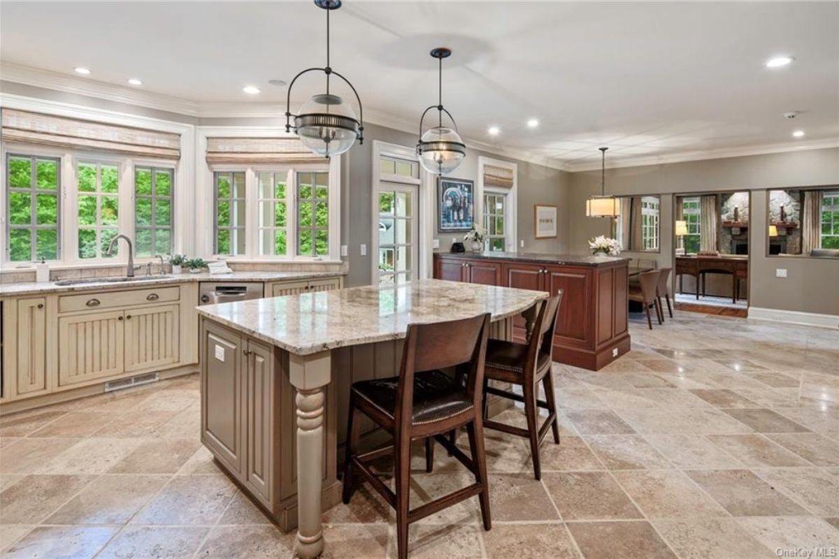 A kitchen with a center island, countertop, sink, and windows.
