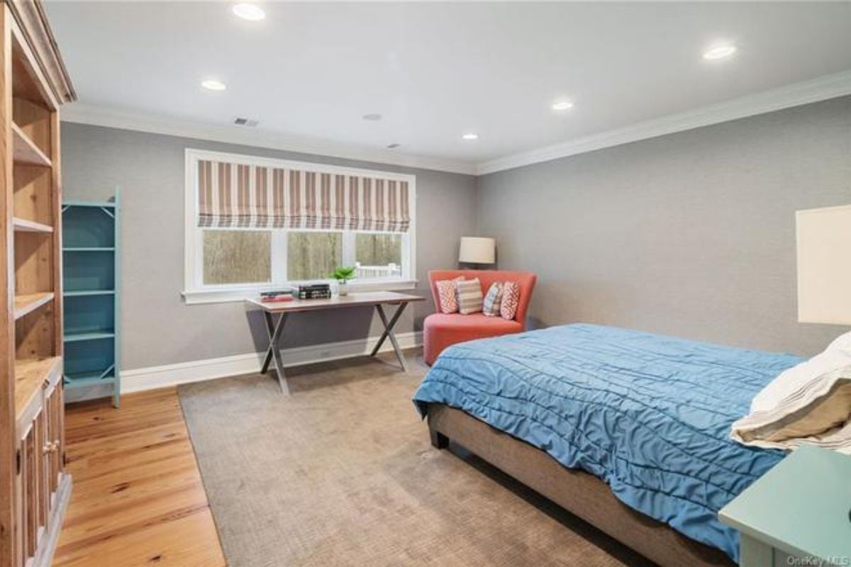 A bedroom with a bed, window, cabinet, shelves, and a chair.