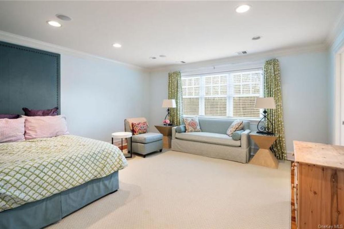 A bedroom with a bed, window, chair, coffee table, and couch.