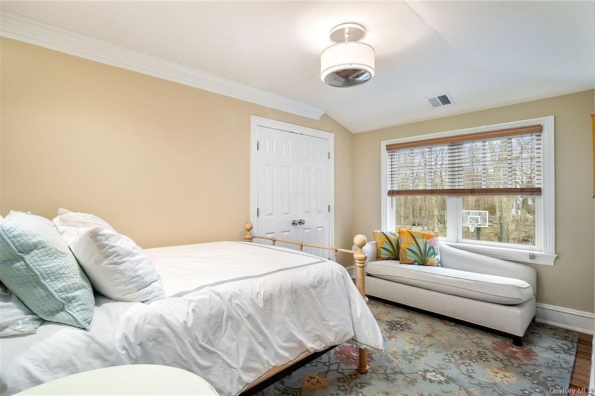 A bedroom with a bed, window, rug, and couch.
