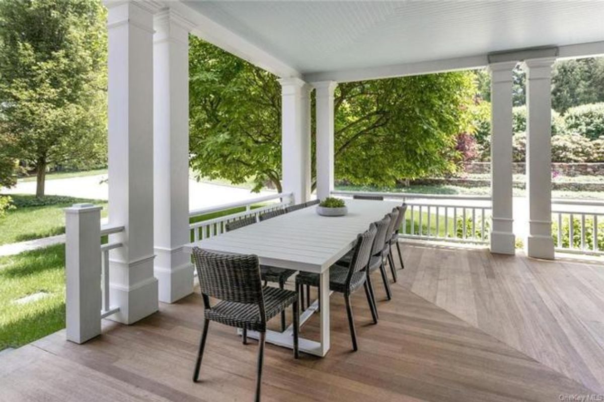 A patio with a long table surrounded by chairs.