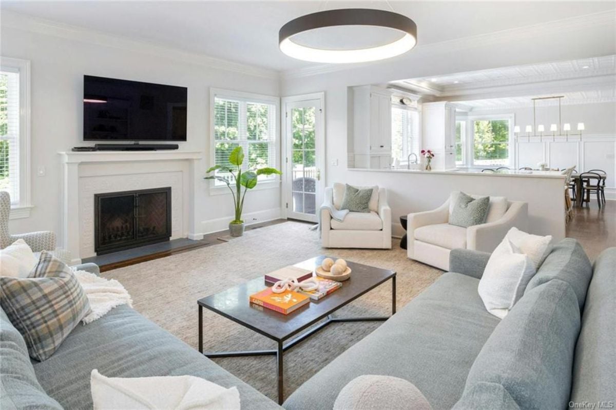 A living room with a TV, fireplace, rug, couches, and a center table.