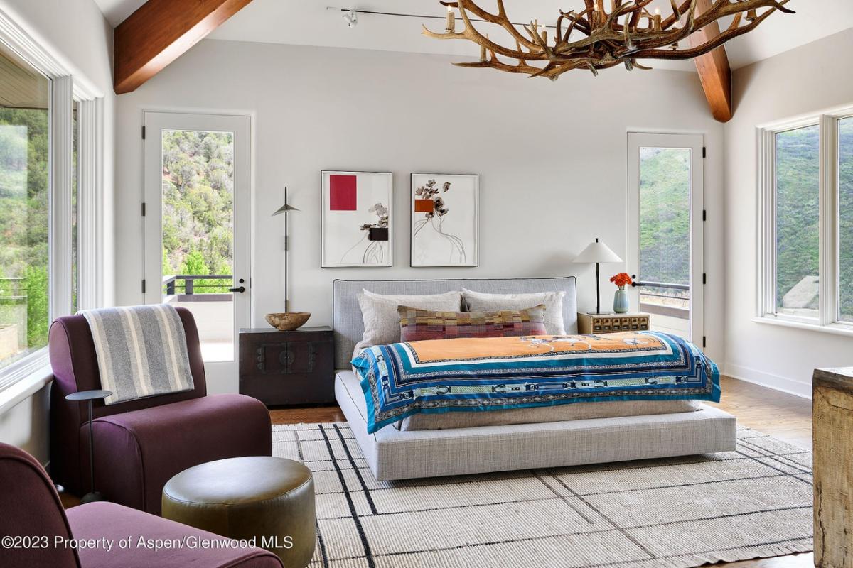 Bedroom with couches, vaulted ceiling and glass windows.