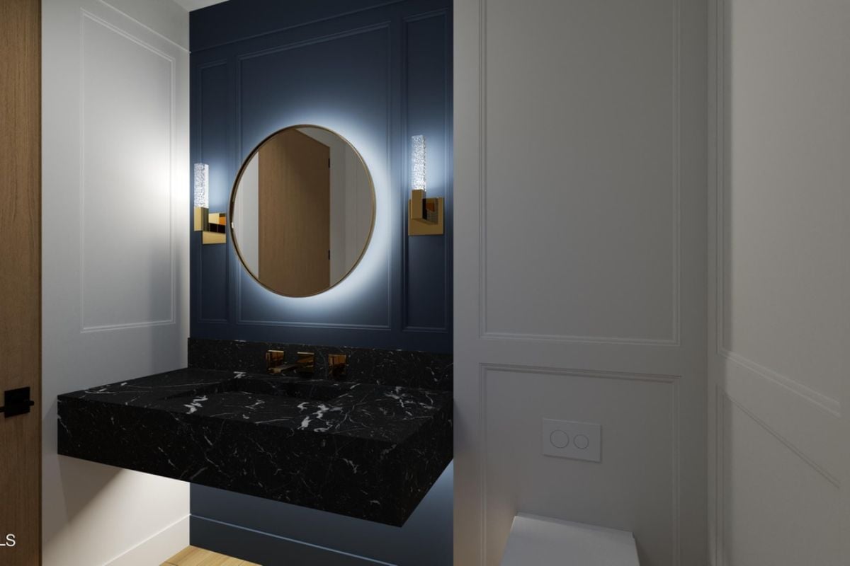 A bathroom with a vanity and a round mirror.