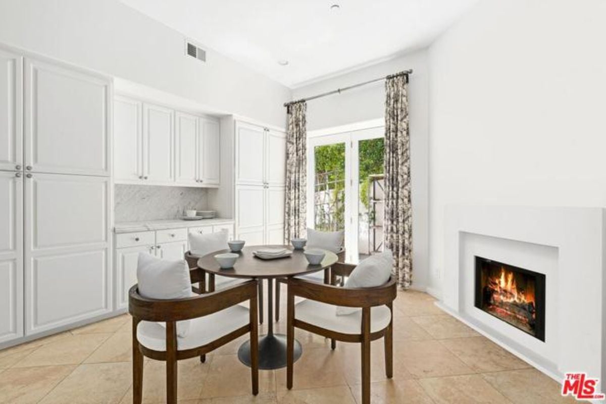 A breakfast nook with a fireplace, cabinets, and a round table with chairs.