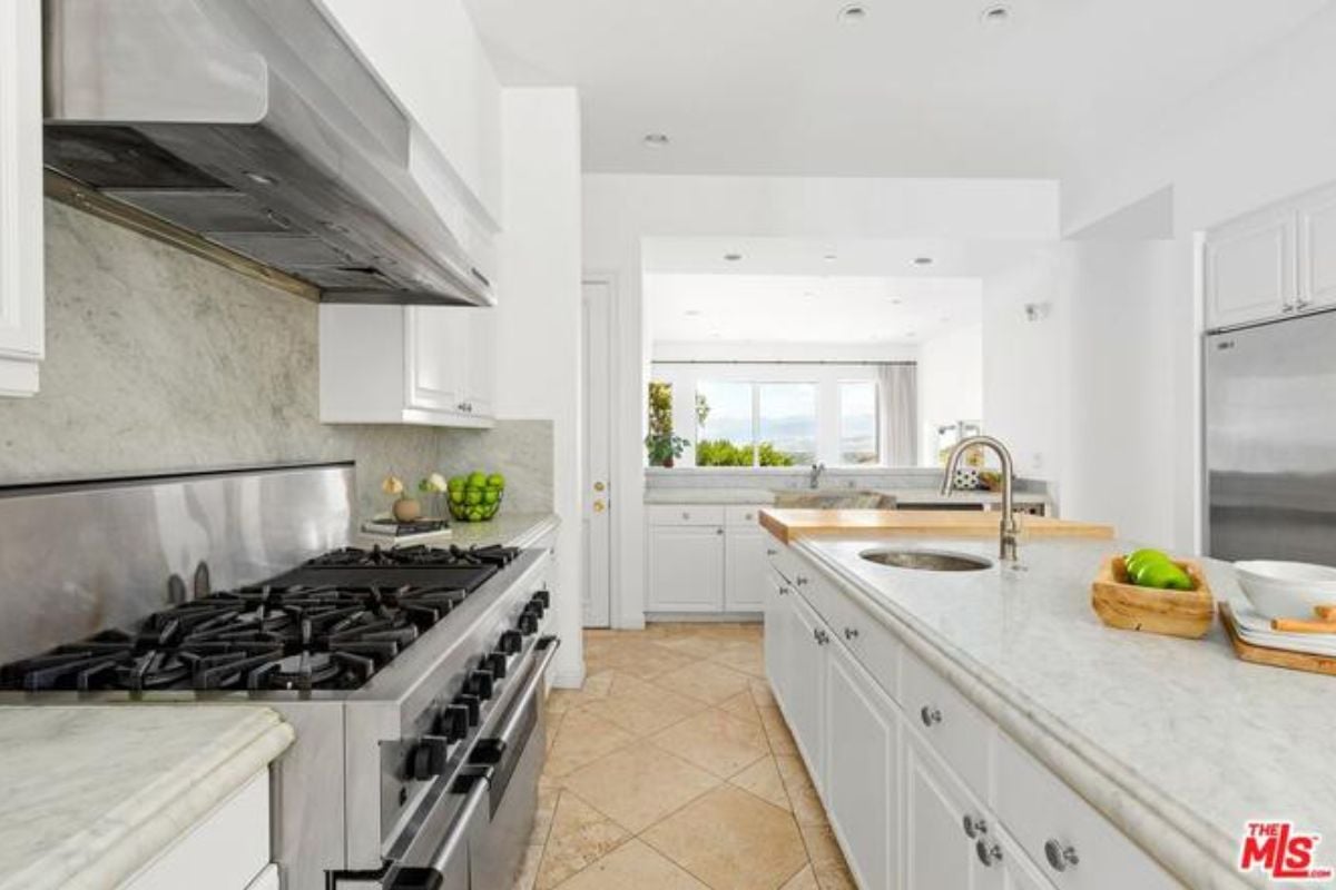 A kitchen with countertops, sink, cabinets, and stove.