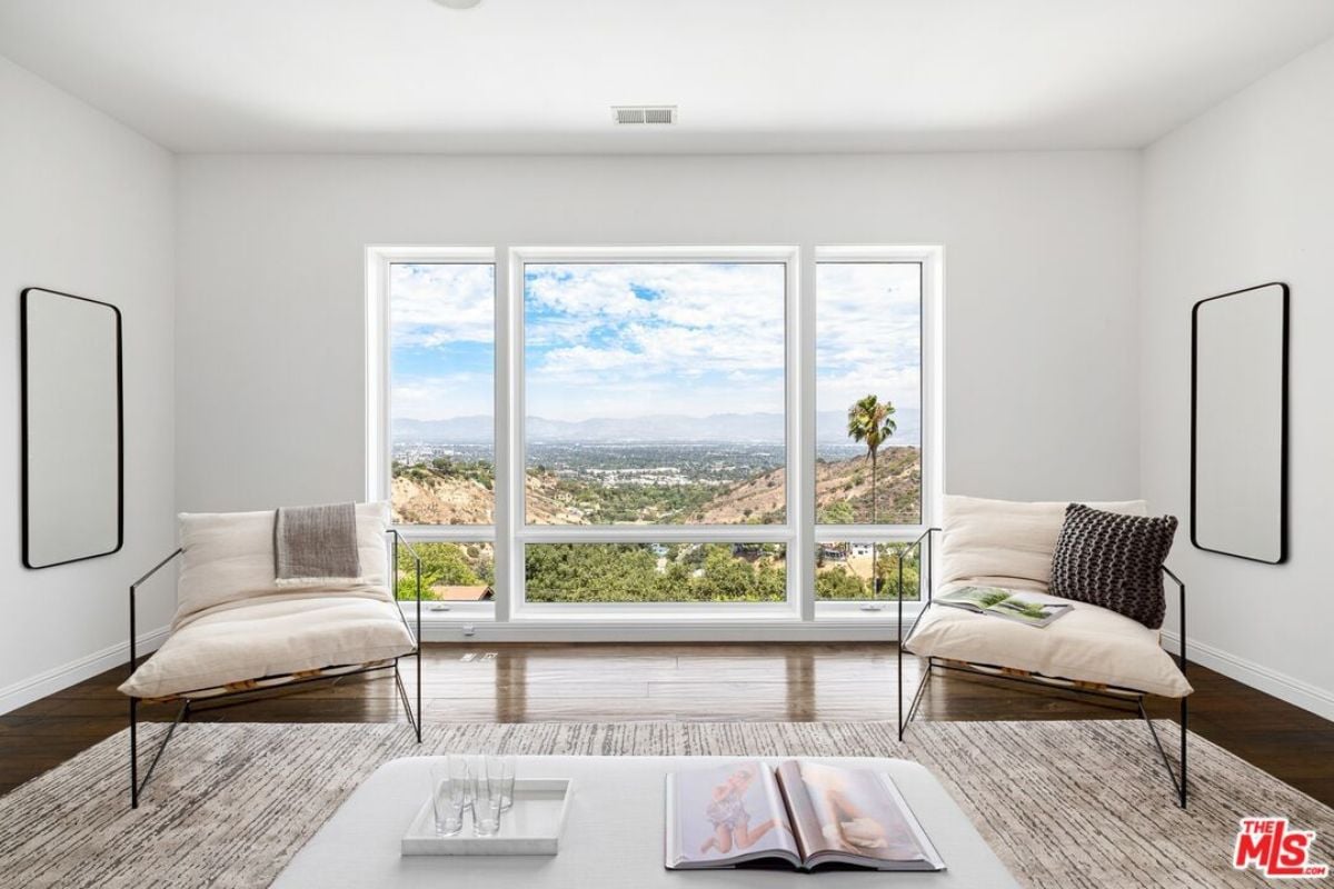 A sitting area with windows, mirrors, and chairs.