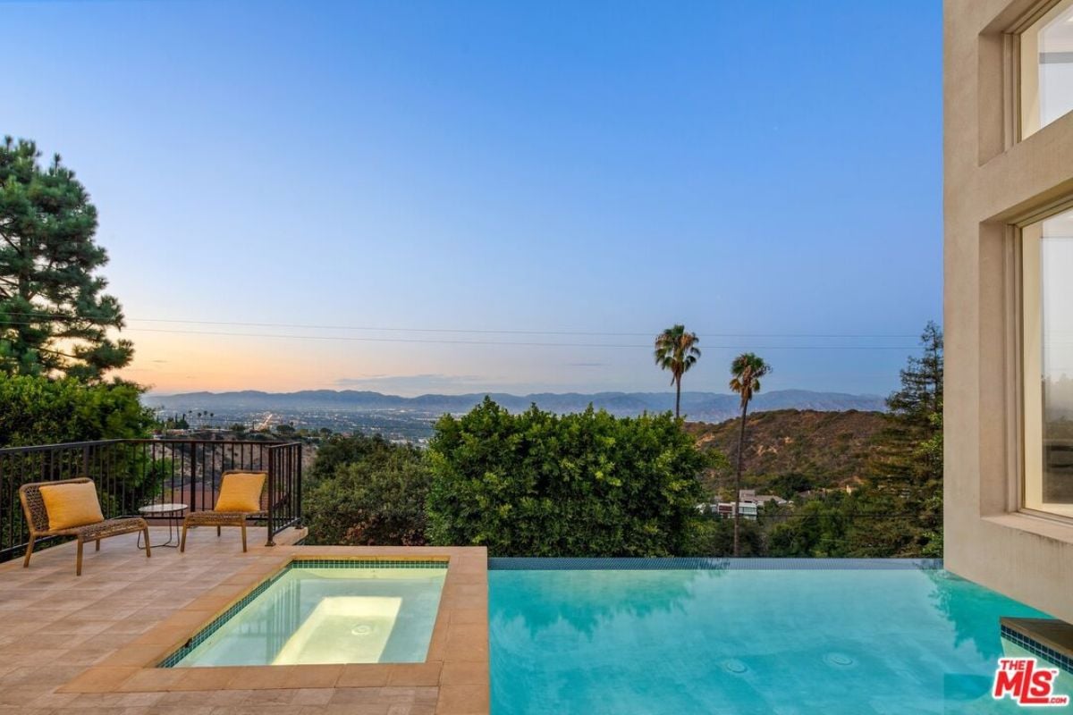 A swimming pool with a jacuzzi and chairs.