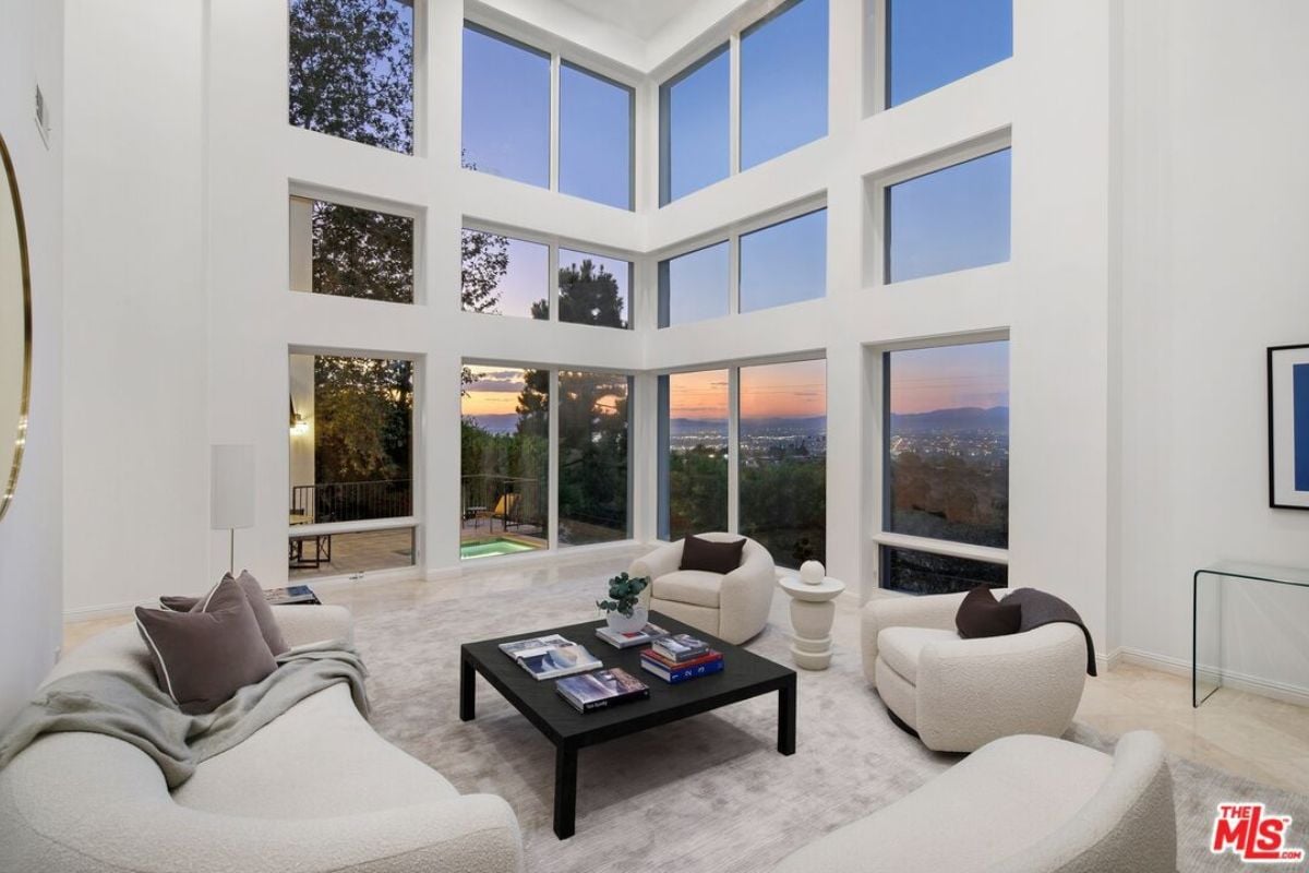 A living room with windows, white couches, and a center table.