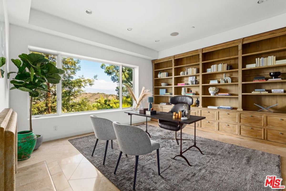 A home office with a potted plant, window, shelves, chairs, and desk.