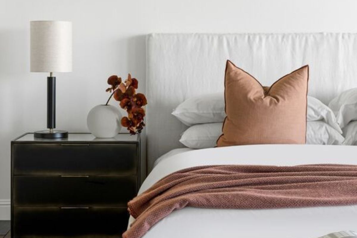 A bedroom with a bed, nightstand, and lampshade.