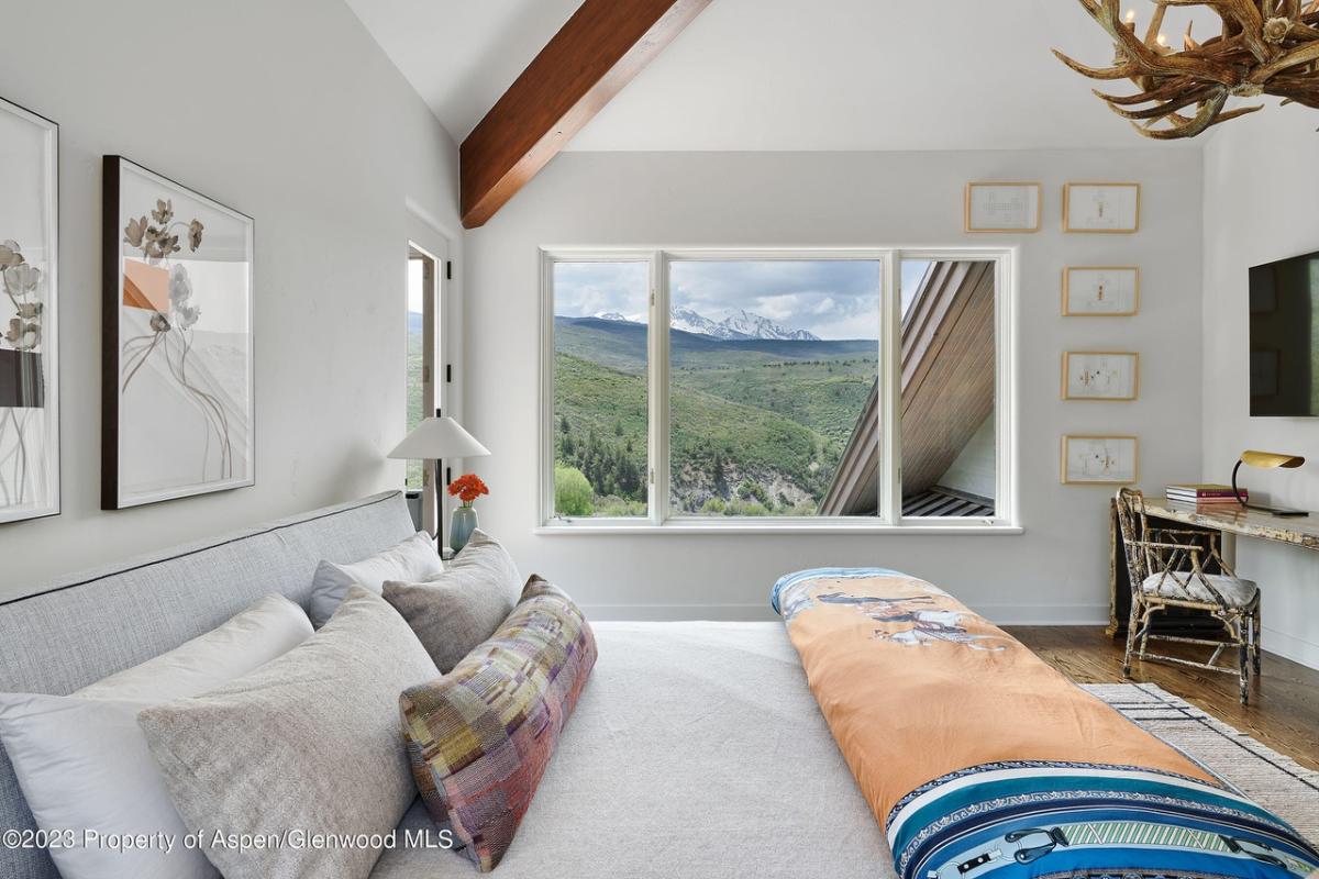 Bedroom with vaulted ceiling and glass windows.