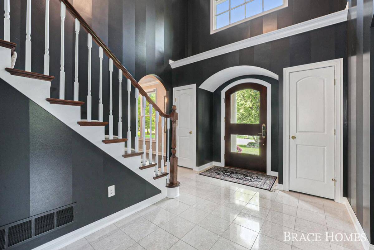 Foyer with a glazed entry door, a staircase, and black walls.