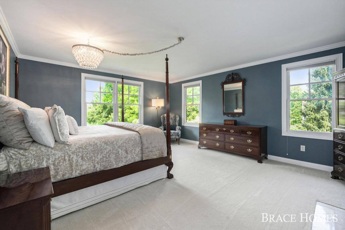 Primary bedroom with a four-poster bed and a dark wood dresser adorned by a decorative mirror.