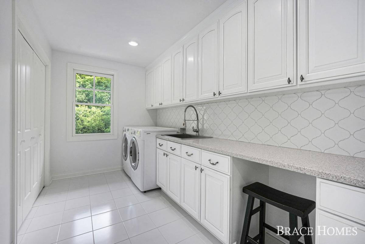 Laundry room with white cabinets, front-load appliances, and a utility sink.
