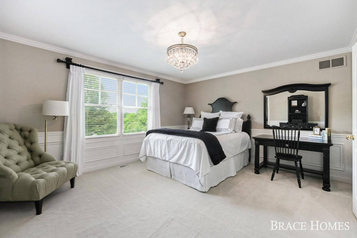 Bedroom with a skirted bed, a tufted chair, and a black desk.