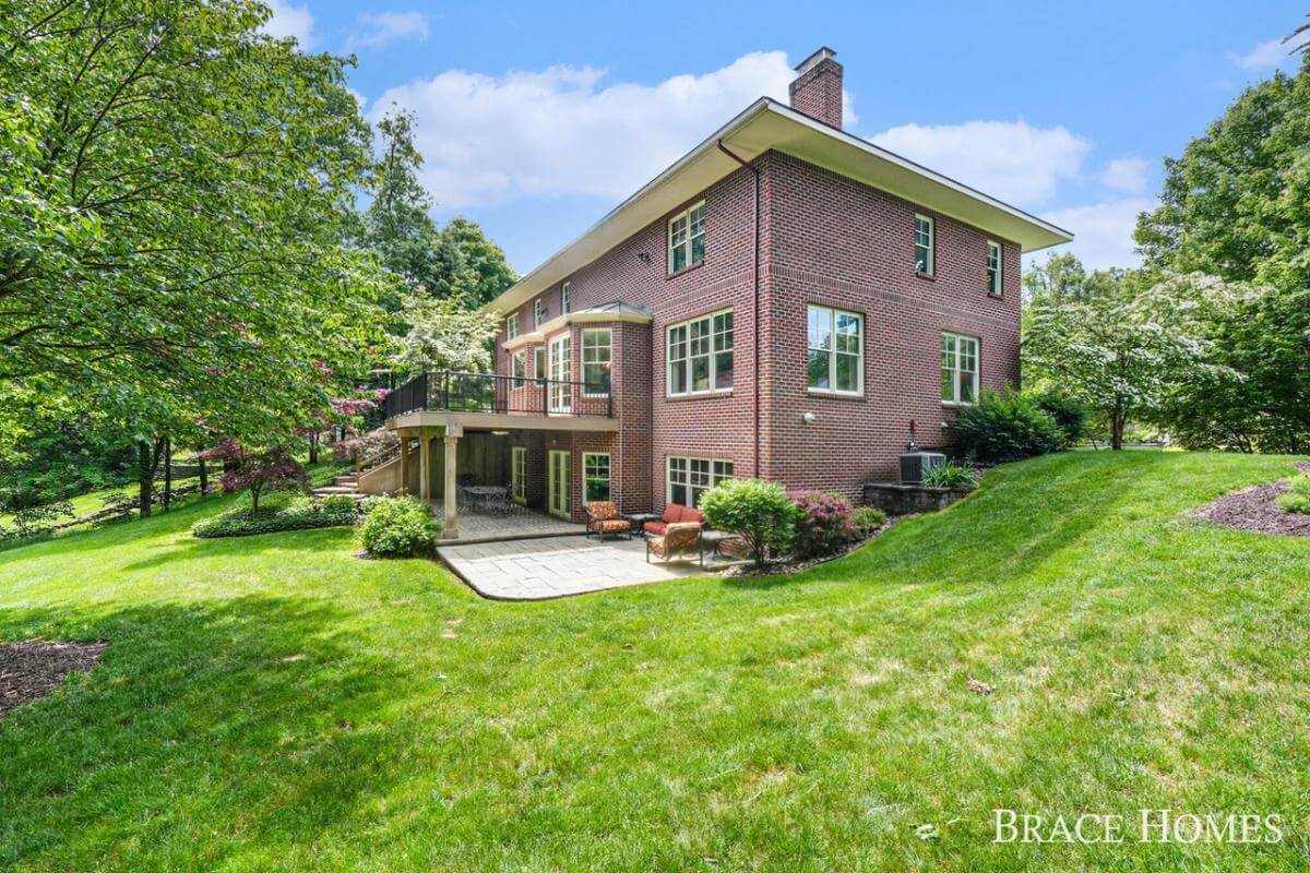 Rear-left view with white-framed windows, a sundeck, and a partially covered patio.