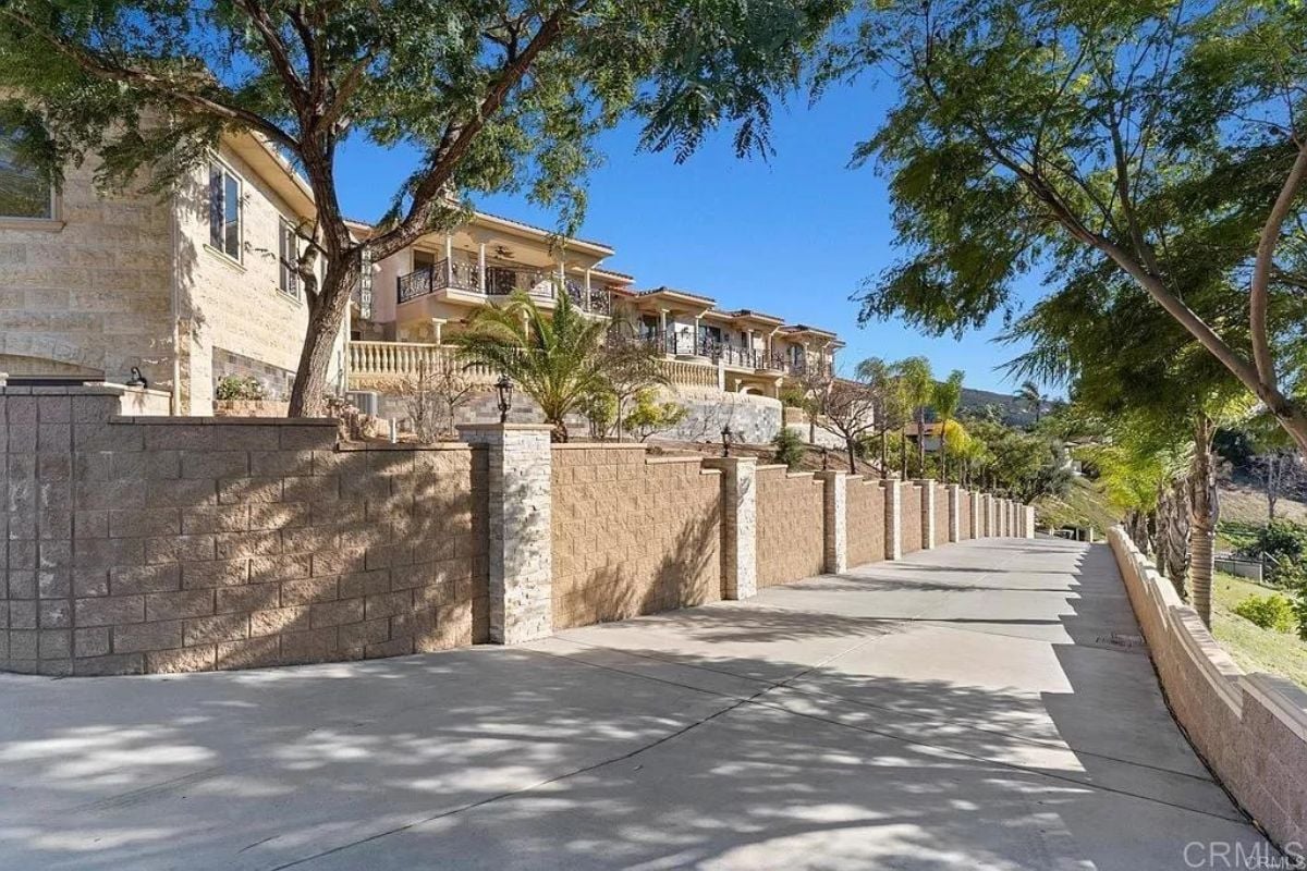 A driveway surrounded by trees and a fence.