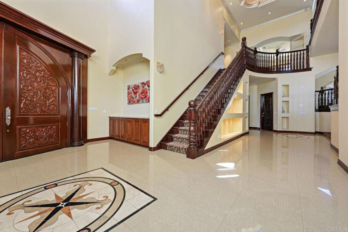A foyer with a tiled floor and staircase.