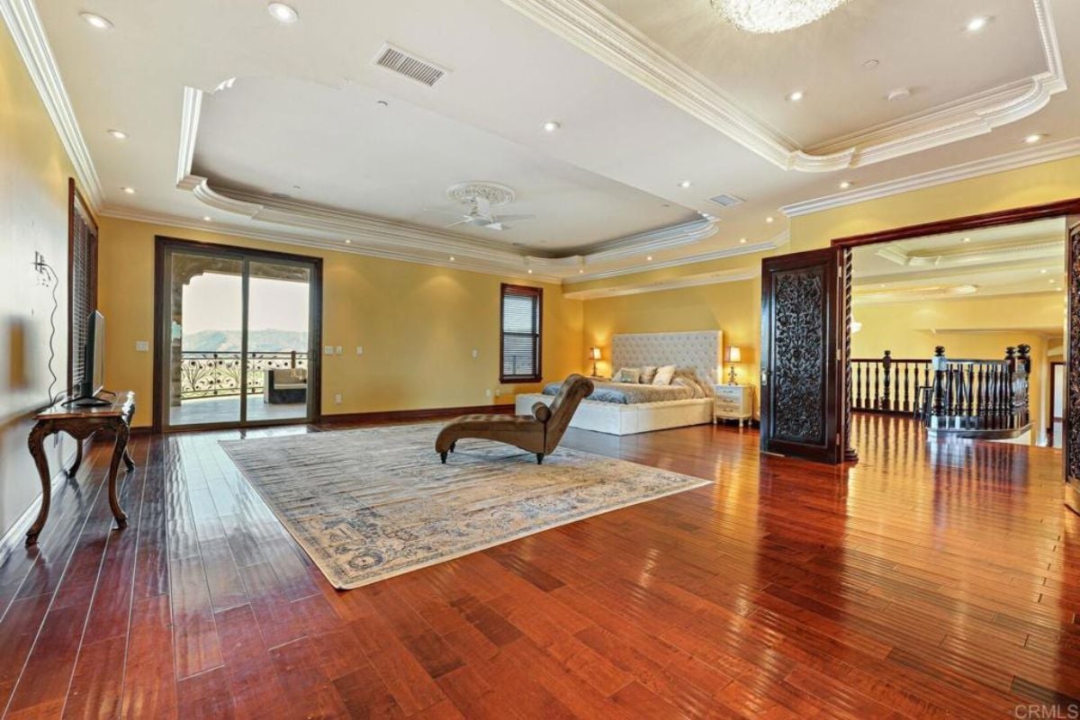 A bedroom with a bed, nightstand, window, rug, and a comfy chair.