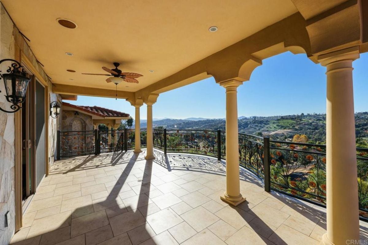 A terrace with columns, a chandelier, and a metal handrail.