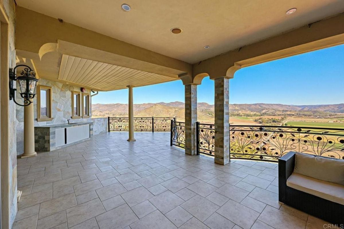 A terrace with columns, a chandelier, and a metal handrail.