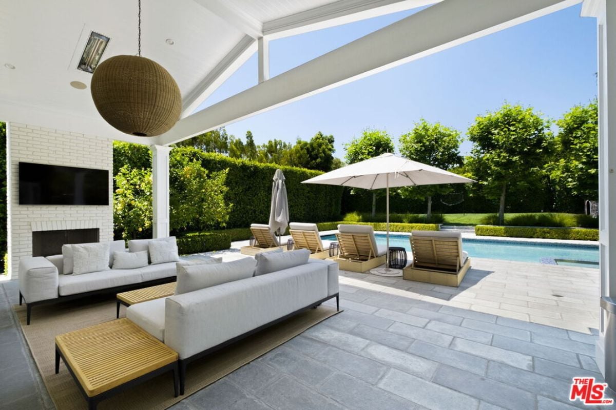 An outdoor living area with a TV, fireplace, couches, and a center table.