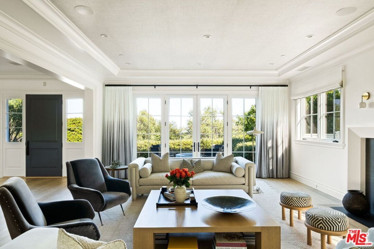 The living room includes windows, a couch, chairs, and a center table.