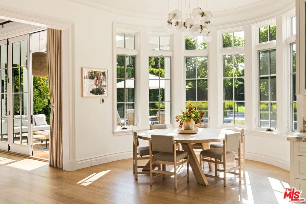 The breakfast nook features windows, a chandelier, and a round table surrounded by chairs.