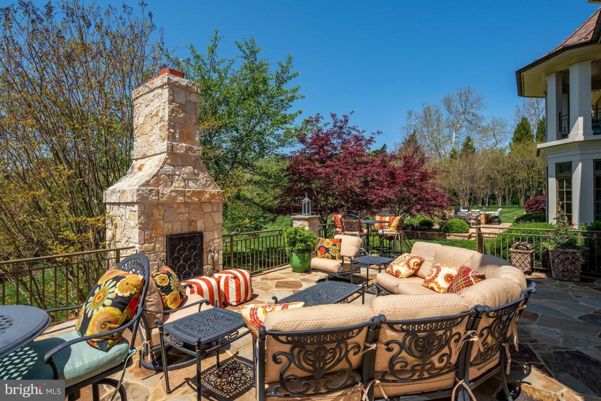 Terrace with tables, chairs and a fireplace.
