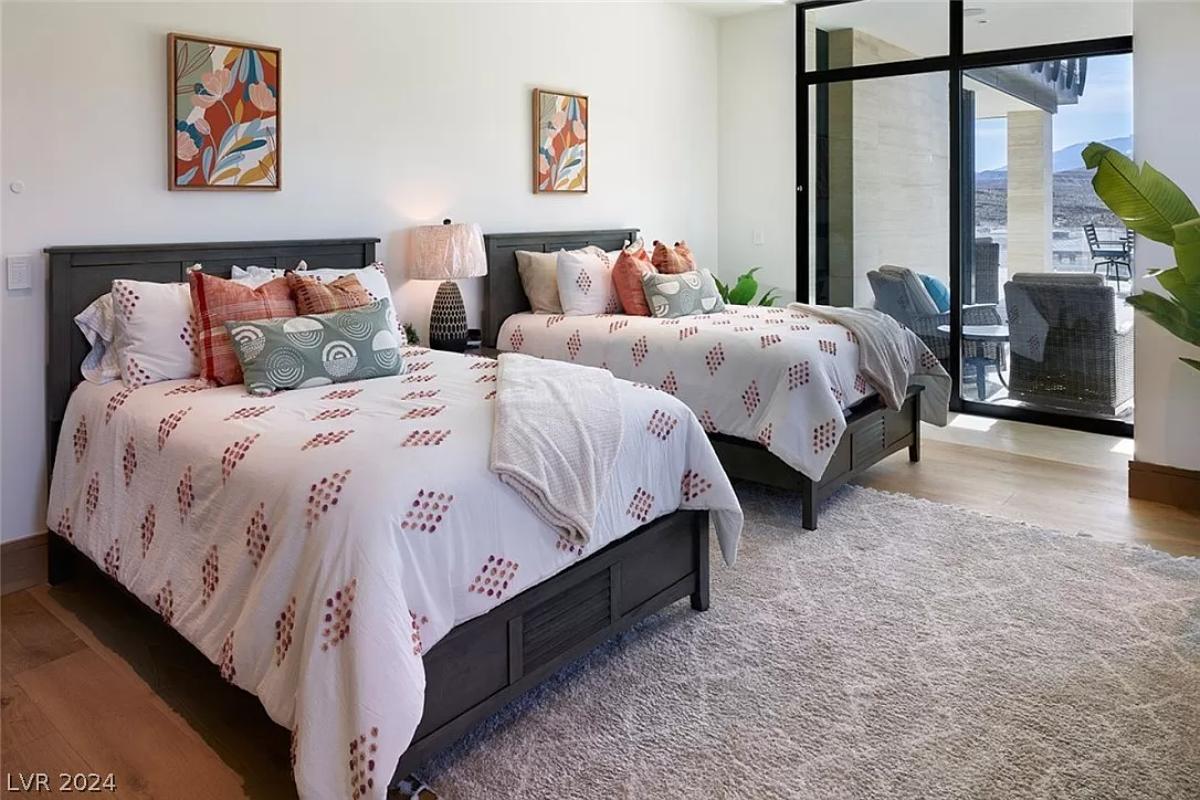 Bedroom with two beds, hardwood flooring and sliding glass doors.
