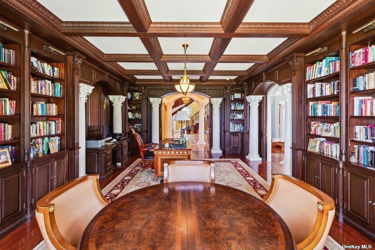 Home office with coffered ceiling, hardwood floors and bookshelves.
