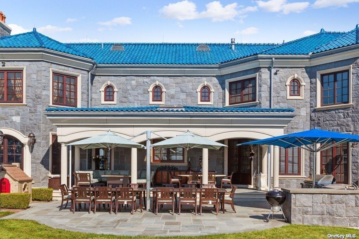 Rear view of the mansion with a patio and a grill area.