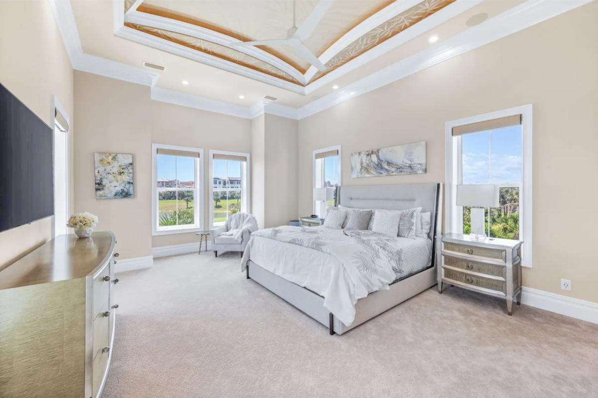 Bedroom with a large bed, glass windows and carpet flooring.