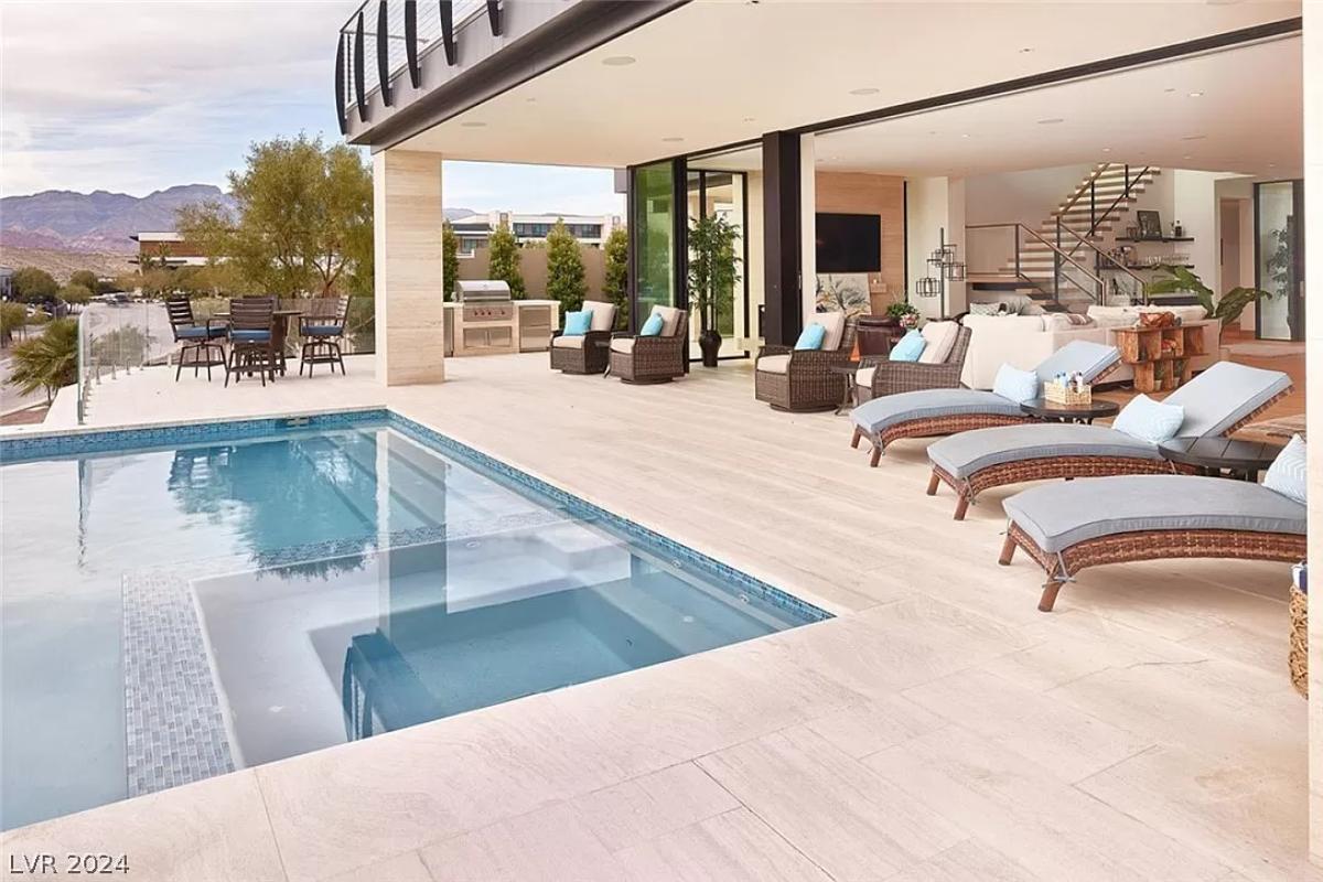 Pool with lounge chairs and a grill area.