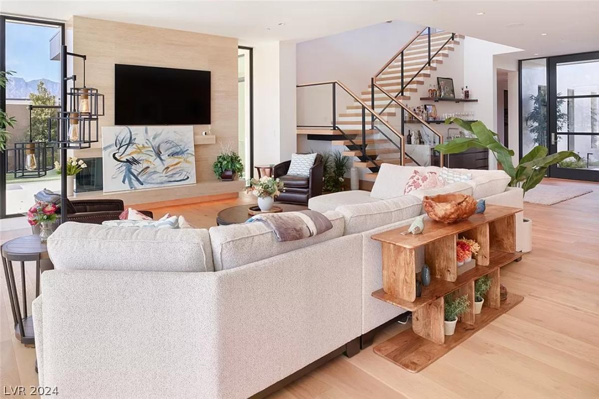 Living room with couches, hardwood floors and custom lighting.