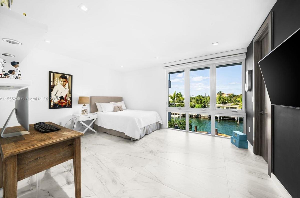 Bedroom with a large bed, a desk, PC and glass windows.