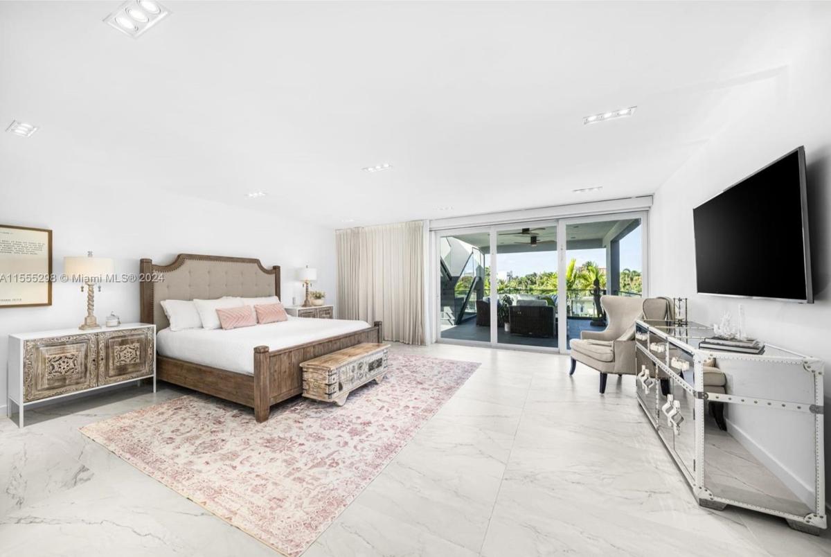Bedroom with a large bed, tile flooring and sliding glass doors.