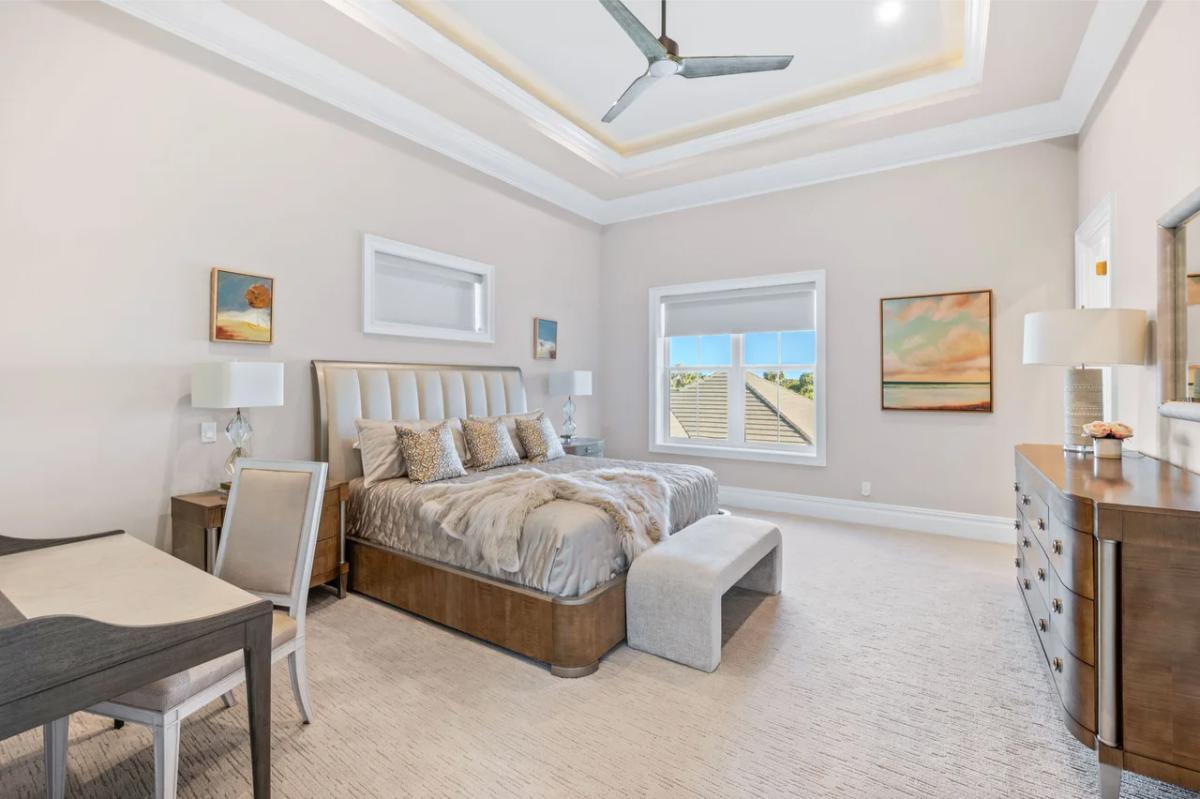 Bedroom with a large bed, glass windows and carpet flooring.