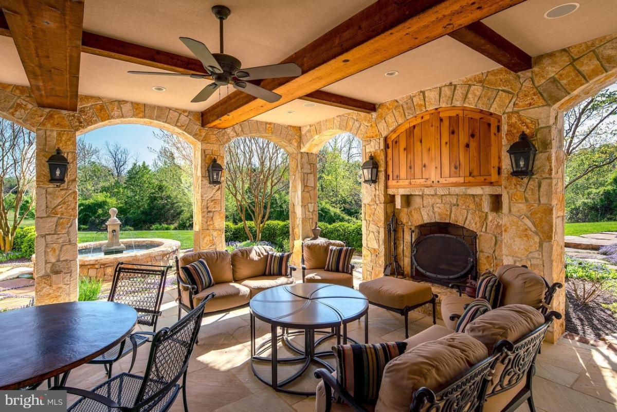 Covered patio with tables, chairs and a fireplace.