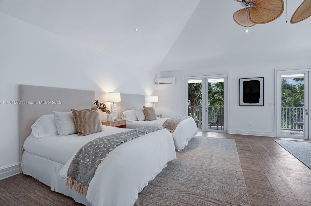 Bedroom with two beds, hardwood flooring and sliding glass doors.