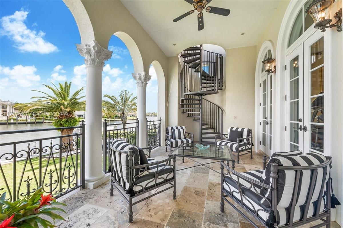 Balcony with a table, chairs and a spiral staircase.