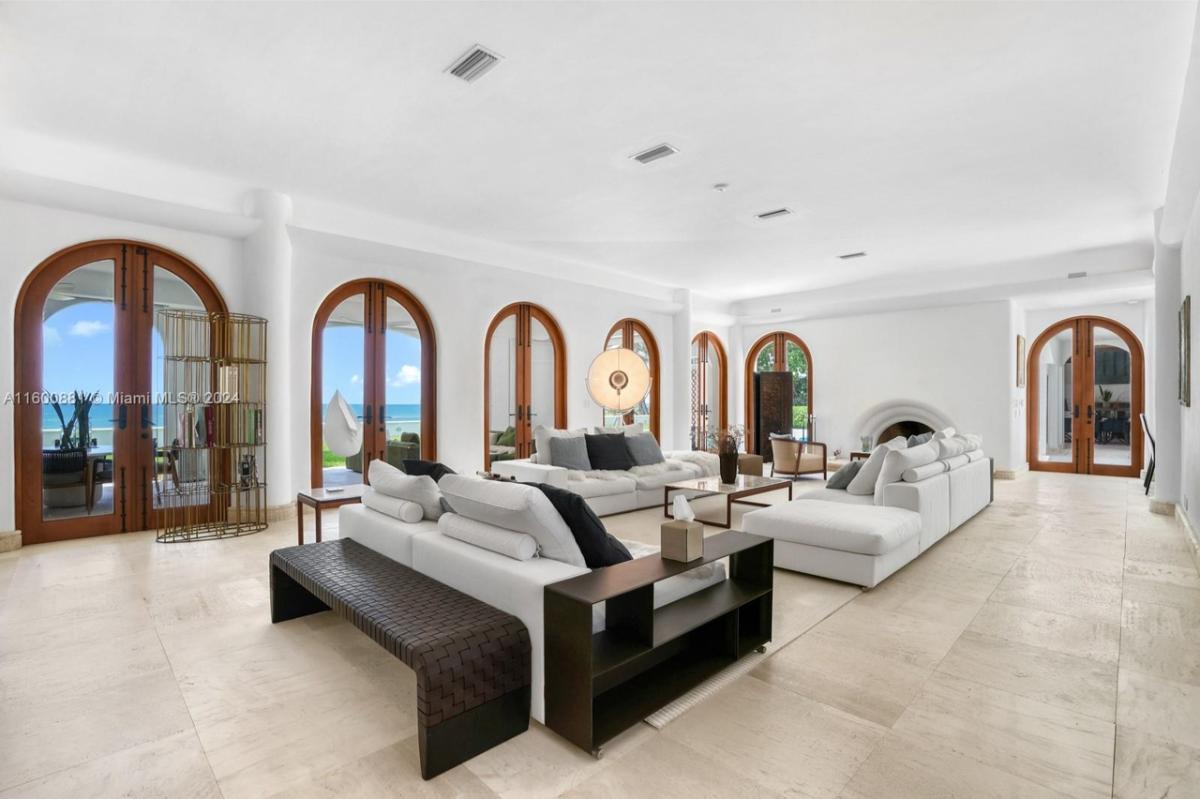 Living room with couches, tile flooring and glass doors.